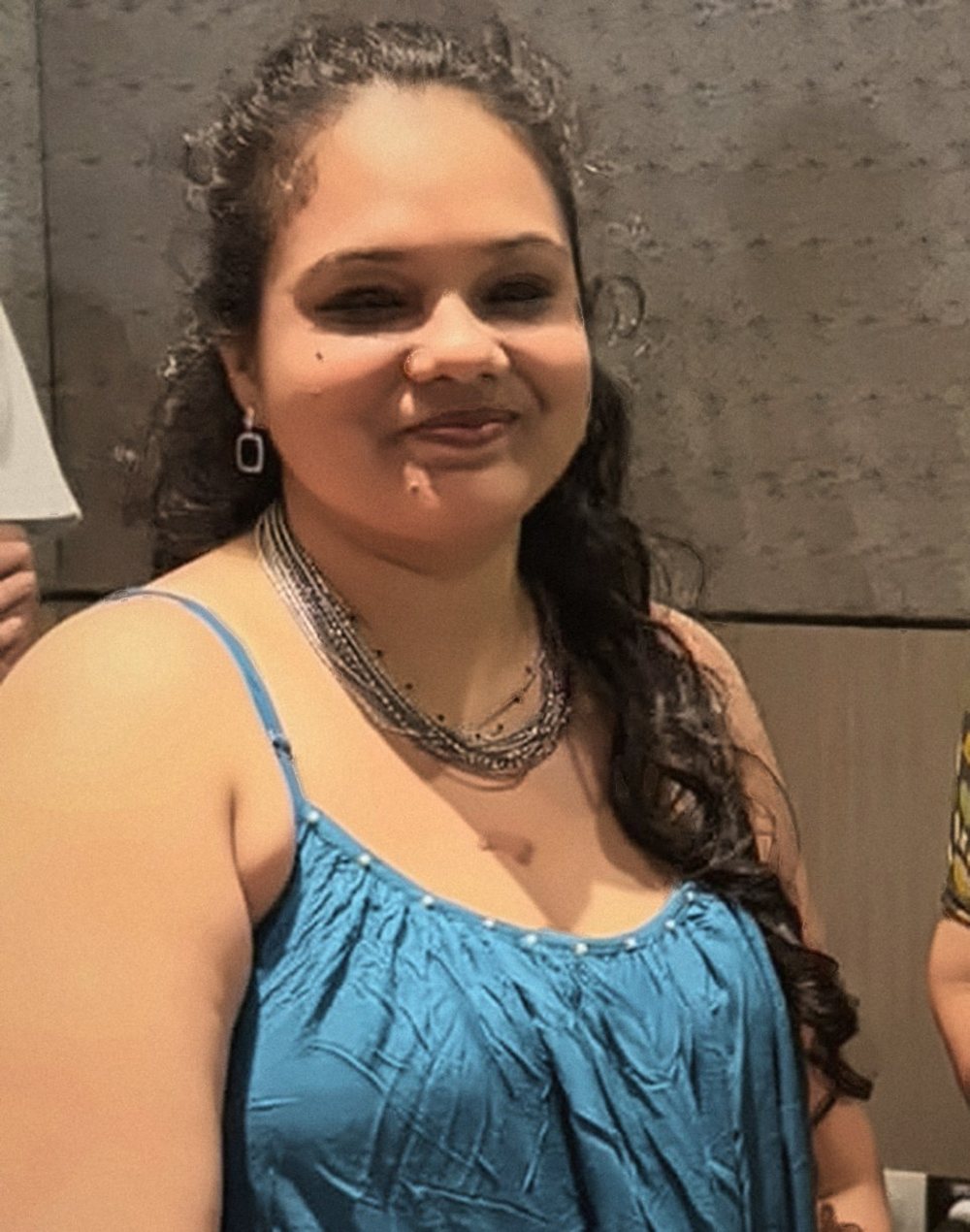 Diviya S Chachra smiling, in a teal dress and layered silver necklaces